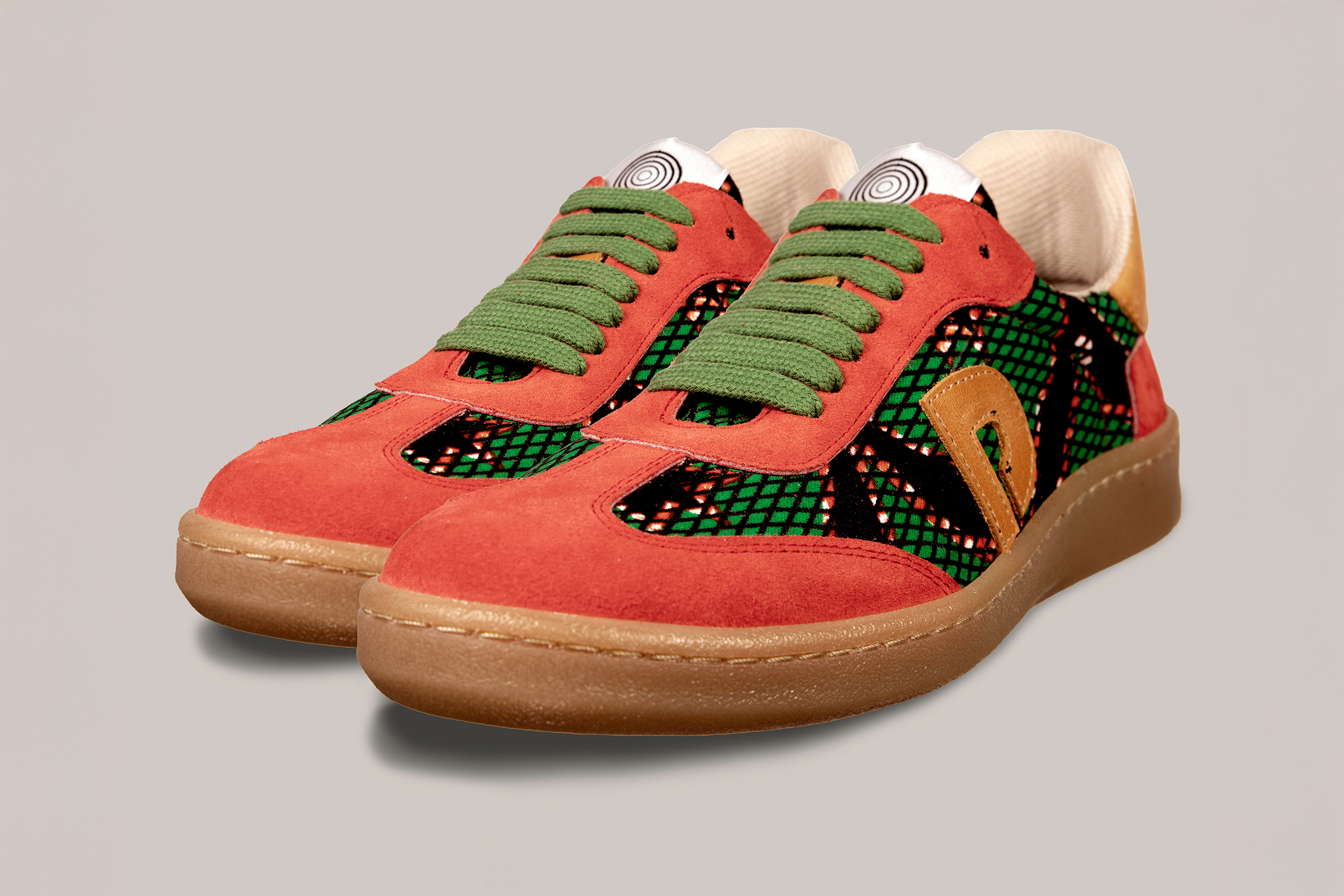 Vista diagonal de las zapatillas unisex Gambia rojas y marrón beige con estampado africano verde