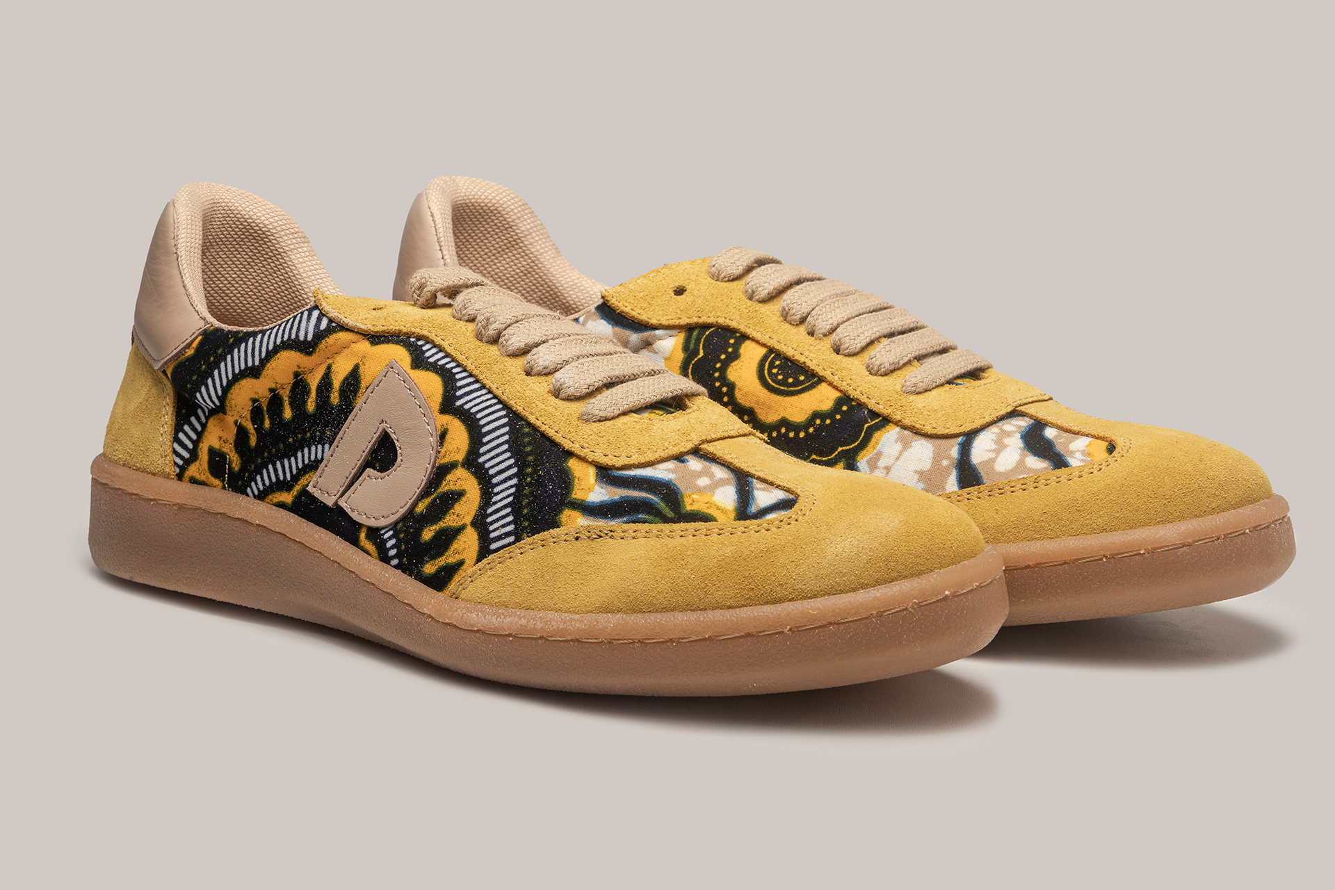 Vista diagonal frontal de zapatillas Senegal amarillo y marrón, diseño con estampados africanos